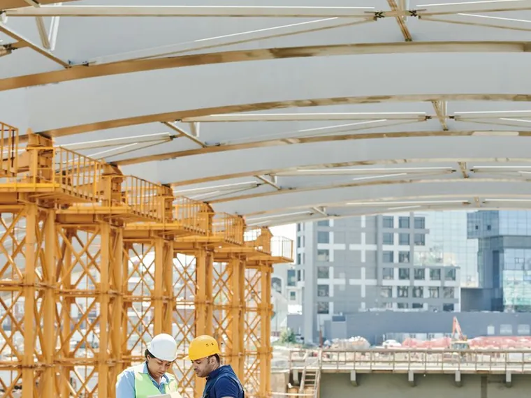 Engineers beneath a large roof structure under construction